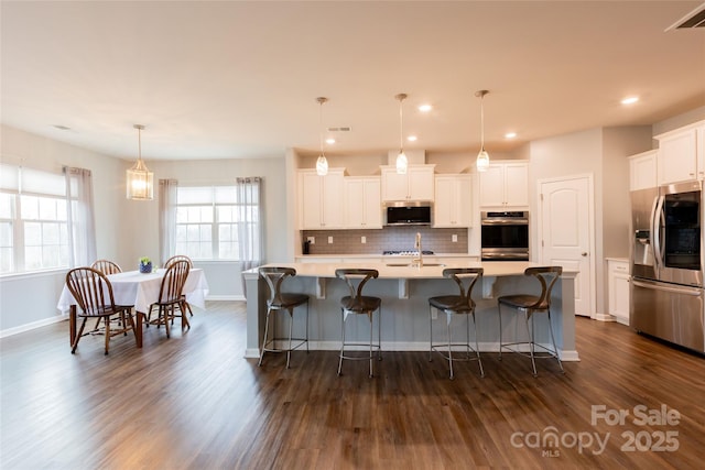 kitchen featuring visible vents, dark wood finished floors, a sink, stainless steel appliances, and light countertops