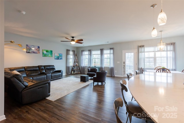 living area with ceiling fan, dark wood-type flooring, and baseboards