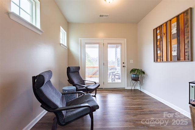 sitting room with dark wood-type flooring, baseboards, and visible vents