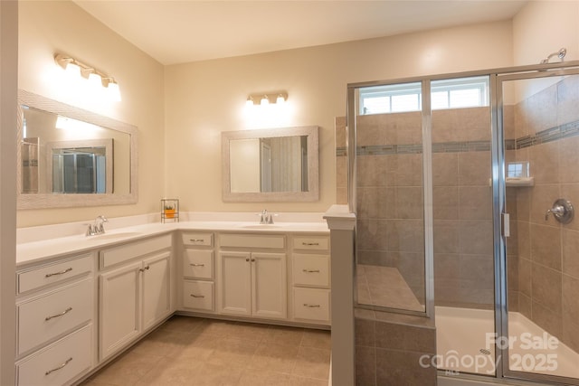 bathroom with tile patterned flooring, double vanity, a tile shower, and a sink