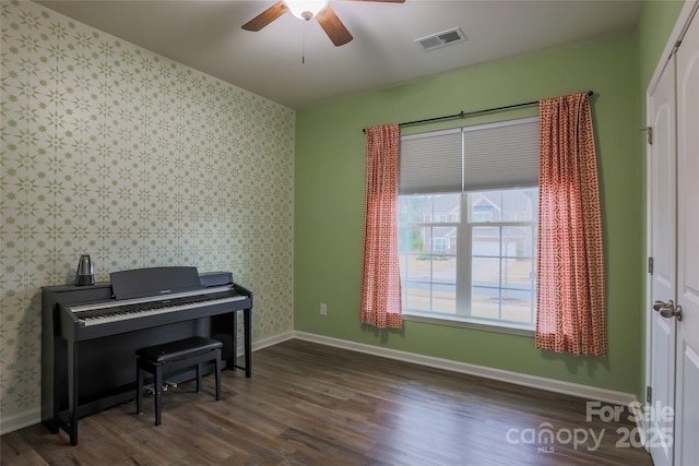 living area featuring visible vents, wallpapered walls, baseboards, wood finished floors, and a ceiling fan