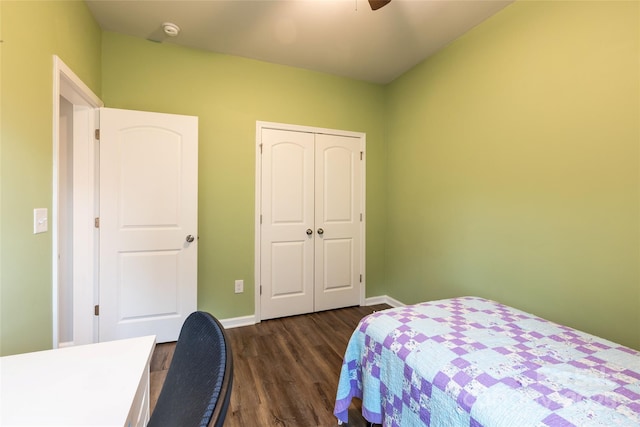 bedroom with a closet, baseboards, dark wood-type flooring, and ceiling fan