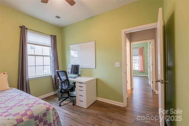 bedroom with dark wood-style floors, multiple windows, and baseboards