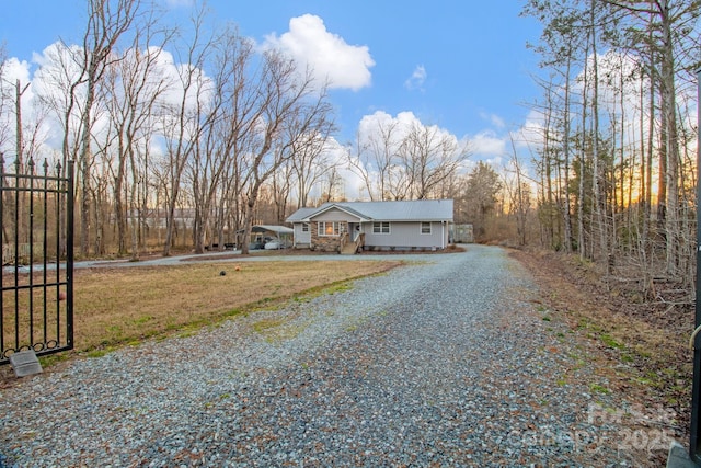 view of front of home with gravel driveway and a front lawn