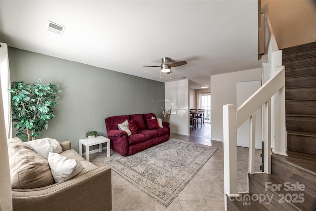 living area featuring stairs, visible vents, and ceiling fan