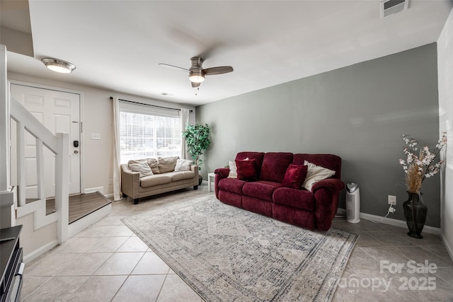 living room with light tile patterned flooring, visible vents, baseboards, and a ceiling fan