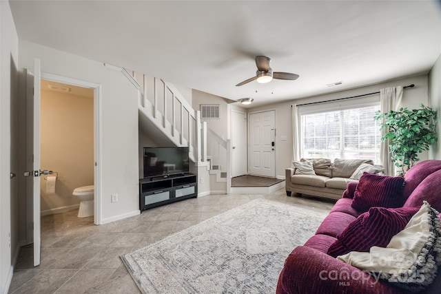 living room featuring stairs, light tile patterned flooring, baseboards, and visible vents