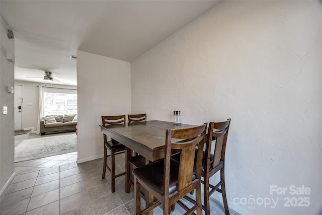 tiled dining space with baseboards and ceiling fan