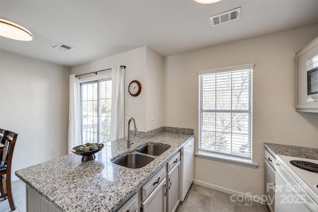 kitchen with dishwasher, a peninsula, visible vents, and a sink