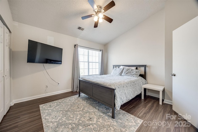 bedroom featuring lofted ceiling, wood finished floors, visible vents, and a textured ceiling