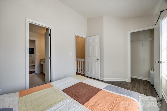 bedroom with wood finished floors, connected bathroom, a closet, radiator, and baseboards