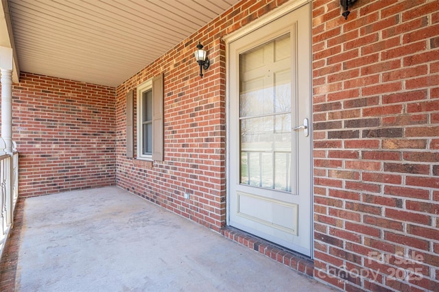 entrance to property with covered porch and brick siding