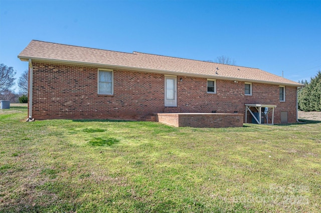 rear view of house featuring brick siding and a lawn