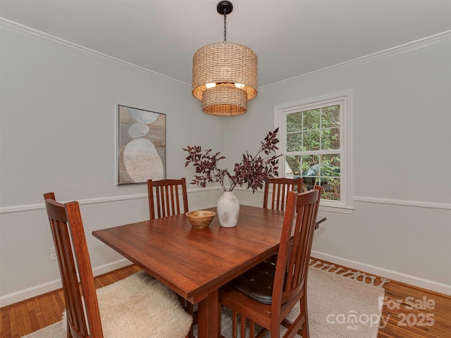 dining space with baseboards, an inviting chandelier, wood finished floors, and crown molding