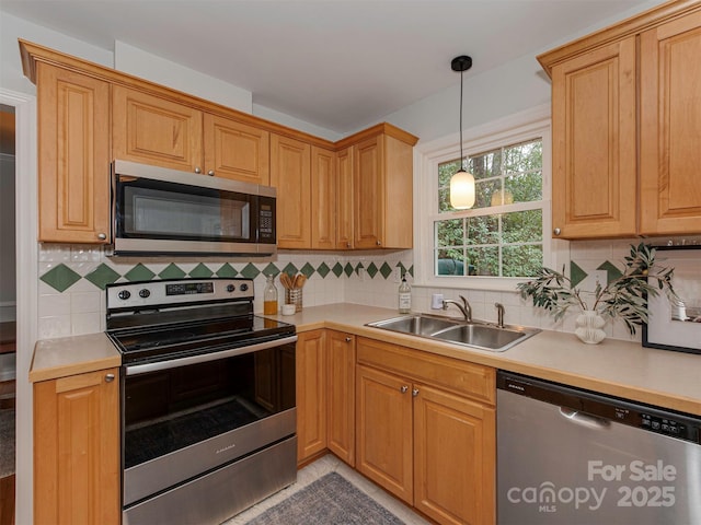 kitchen with a sink, stainless steel appliances, backsplash, and hanging light fixtures