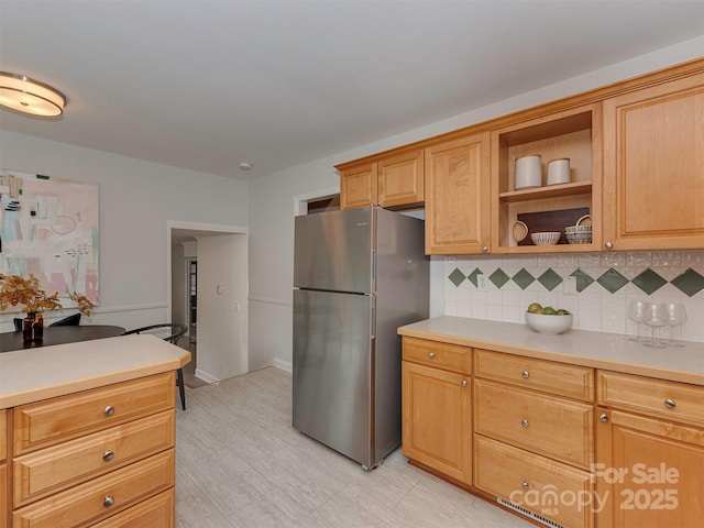 kitchen featuring backsplash, light countertops, freestanding refrigerator, and open shelves