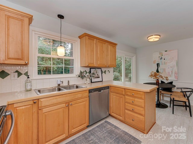 kitchen featuring a sink, stainless steel dishwasher, backsplash, a peninsula, and stove