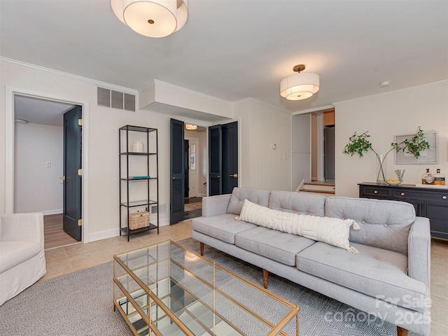 living room with light tile patterned floors, visible vents, baseboards, and ornamental molding