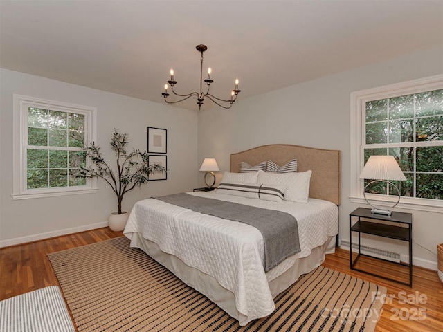 bedroom featuring baseboards, an inviting chandelier, and wood finished floors