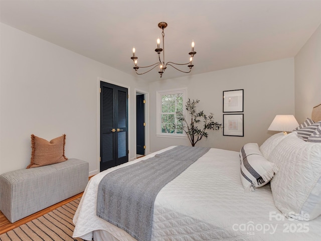 bedroom with light wood-type flooring, a closet, and a chandelier