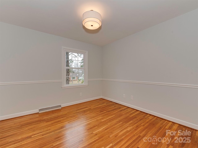 unfurnished room featuring light wood-style floors, visible vents, and baseboards