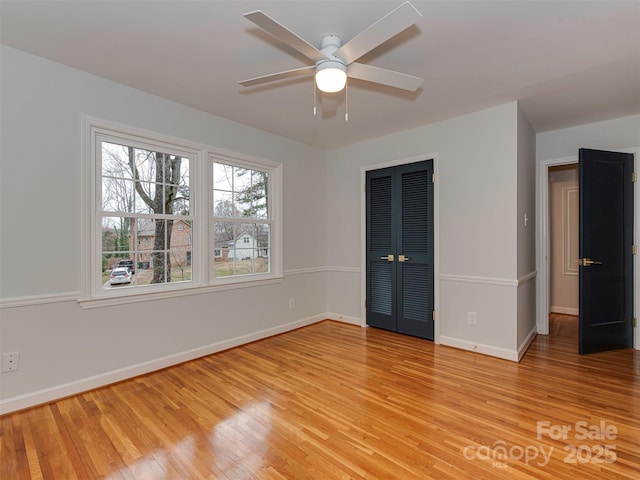 empty room featuring ceiling fan, light wood-type flooring, and baseboards