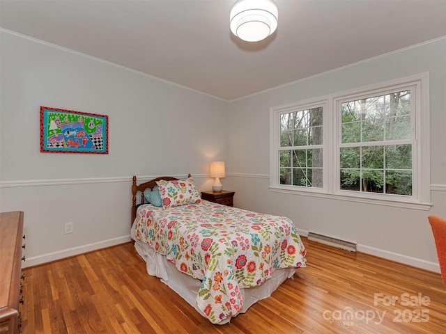 bedroom featuring crown molding, wood finished floors, visible vents, and baseboards