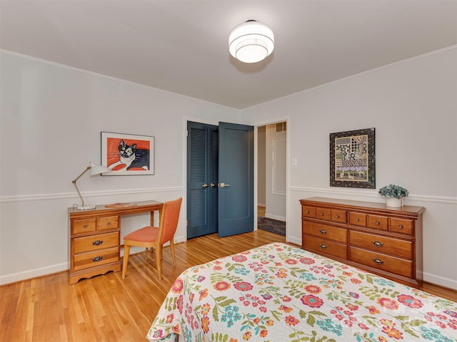 bedroom featuring light wood finished floors, baseboards, and ornamental molding