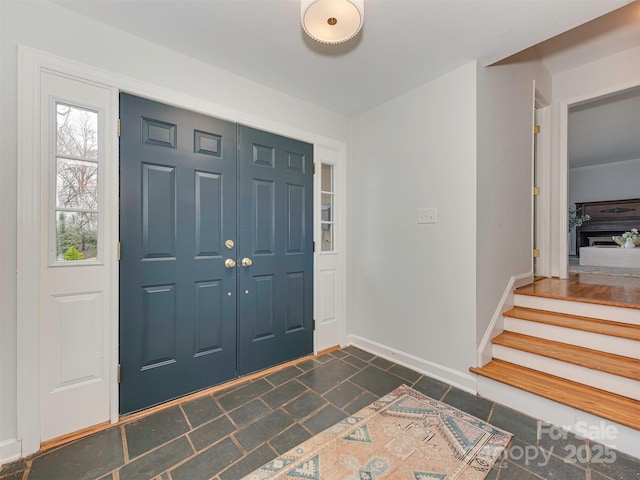 foyer entrance featuring baseboards and stone tile floors