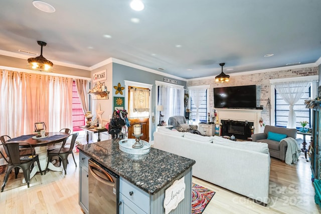 kitchen featuring a glass covered fireplace, open floor plan, light wood finished floors, and ornamental molding