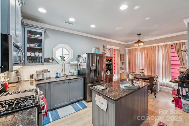 kitchen featuring crown molding, light wood-style flooring, appliances with stainless steel finishes, and a sink