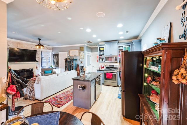 kitchen featuring visible vents, light wood-style flooring, appliances with stainless steel finishes, a glass covered fireplace, and crown molding