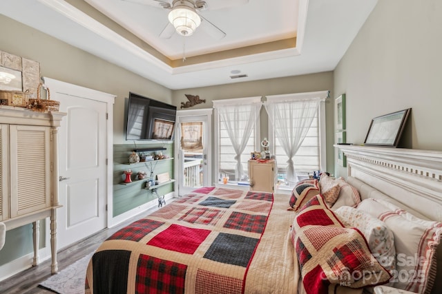 bedroom featuring a raised ceiling, access to outside, wood finished floors, and ceiling fan