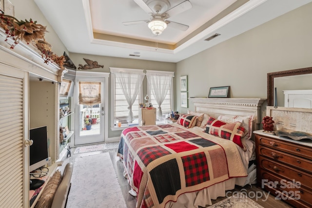 bedroom with a tray ceiling, access to outside, visible vents, and ceiling fan