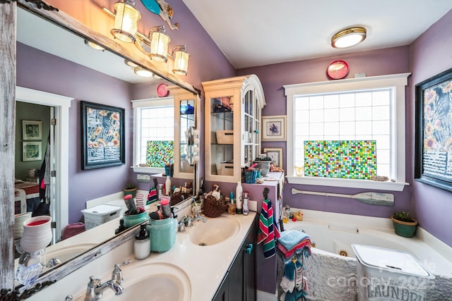 bathroom featuring double vanity, a jetted tub, and a sink