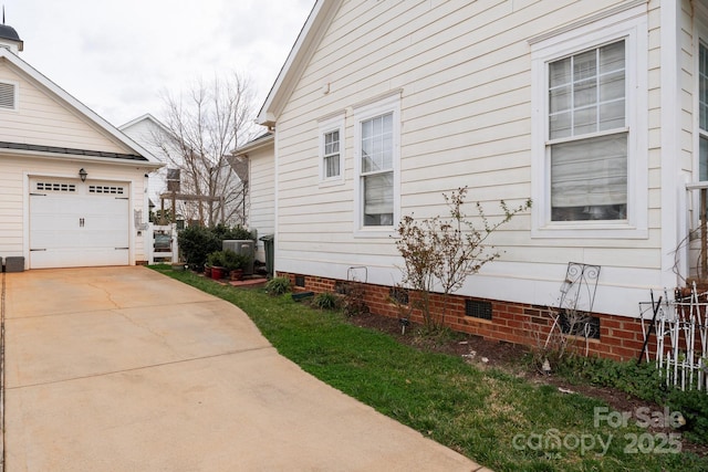 view of side of home with crawl space, a garage, and driveway