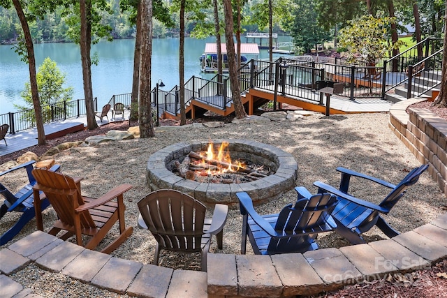 view of patio featuring a fire pit, a water view, and a boat dock