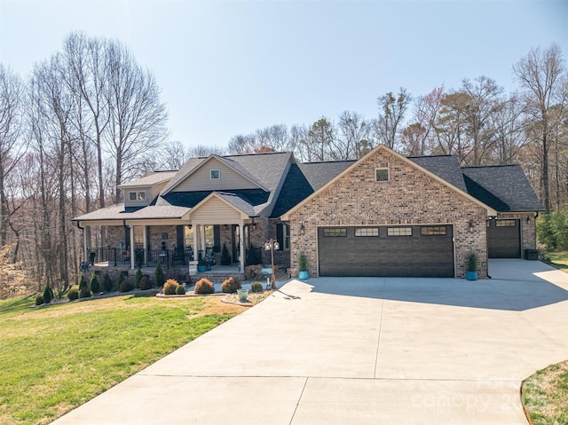 craftsman house featuring brick siding, a front yard, covered porch, a garage, and driveway