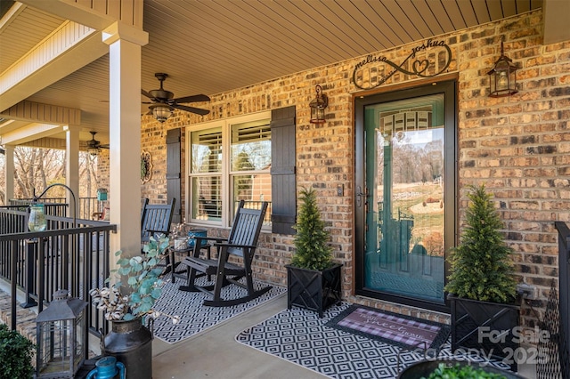 entrance to property featuring brick siding, covered porch, and a ceiling fan