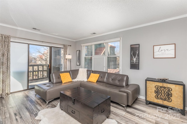 living area with visible vents, a textured ceiling, wood finished floors, and crown molding