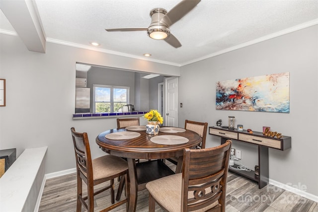 dining area featuring crown molding, wood finished floors, baseboards, and a textured ceiling