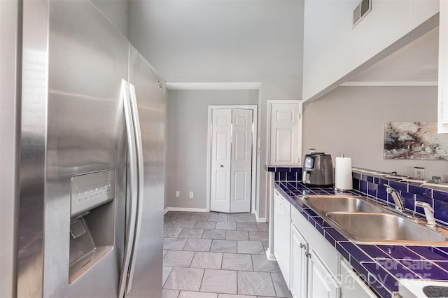 kitchen with visible vents, ornamental molding, a sink, white cabinetry, and stainless steel fridge