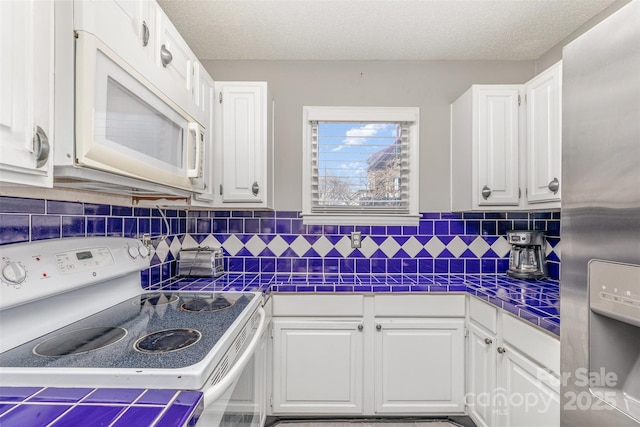 kitchen with tasteful backsplash, tile countertops, white cabinets, white appliances, and a textured ceiling