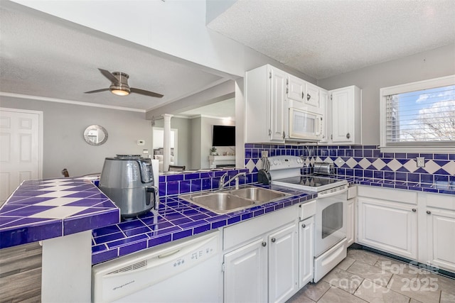 kitchen with a sink, backsplash, tile countertops, white appliances, and white cabinets