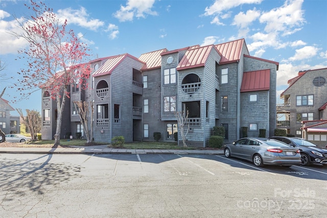 view of front of property with a standing seam roof, uncovered parking, and metal roof