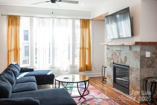 living room with baseboards, recessed lighting, wood finished floors, a glass covered fireplace, and a ceiling fan