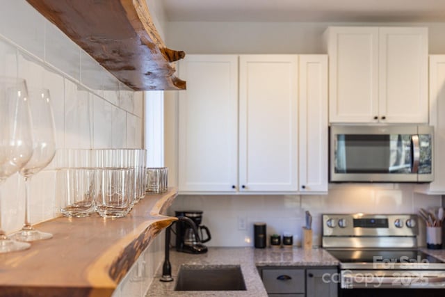 kitchen with white cabinetry, light stone counters, appliances with stainless steel finishes, and a sink