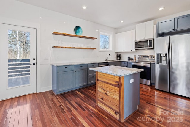 kitchen featuring a kitchen island, recessed lighting, appliances with stainless steel finishes, light stone countertops, and dark wood-style flooring