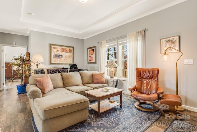 living room with baseboards, crown molding, a tray ceiling, and wood finished floors