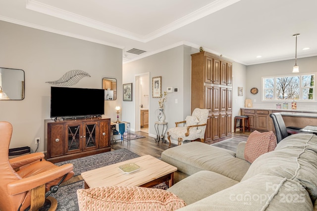 living room featuring baseboards, wood finished floors, visible vents, and ornamental molding